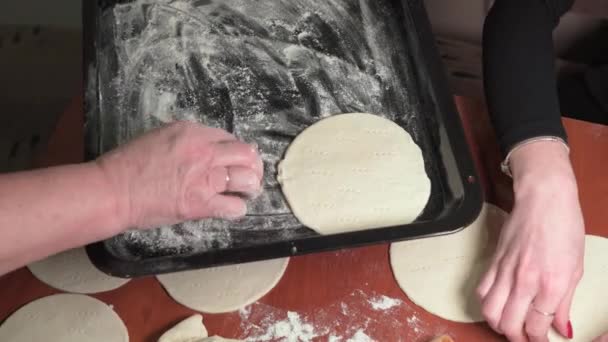 孫娘と祖母がシンプルなパンケーキを作っています 彼らは慎重にオーブンで焼くためにベーキングシートにそれらを配置します — ストック動画