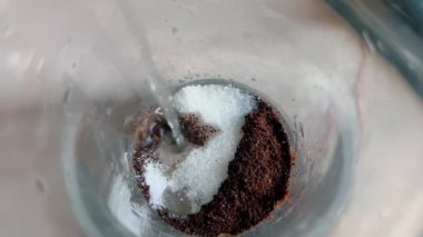 Kaynar su, içinde kahve ve şeker bulunan bir bardağa dökülür..