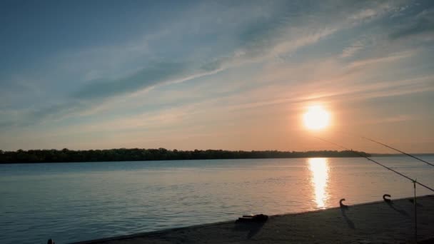 Zachód Słońca Pobliżu Spokojnej Rzeki Brzegach Której Znajdują Się Wędki — Wideo stockowe