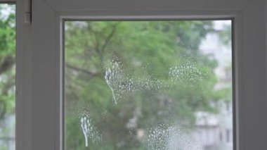 Evdeki pencereleri özel bir fırça ve temizlik sıvısıyla temizleme işlemi.