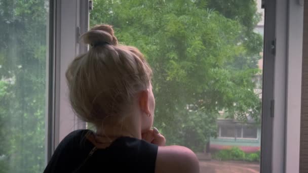 Una Ragazza Triste Guarda Fuori Dalla Finestra Durante Pioggia Maltempo — Video Stock