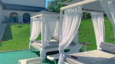 Güneşli bir günde evin arka bahçesinde perdeleri olan boş oturma yerleri.