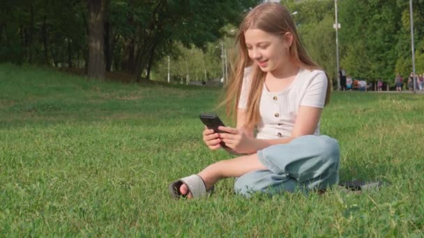 Молодая Веселая Девушка Сидящая Траве Общается Друзьями Видеосвязи — стоковое видео