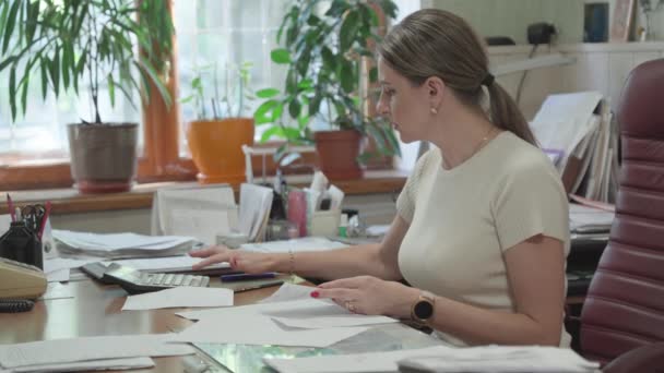 Geschäftsfrau Schreibtisch Arbeitet Mit Dokumenten Und Berechnet Finanzen Auf Taschenrechner — Stockvideo