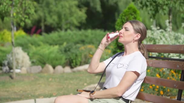Женщина Средних Лет Сидящая Скамейке Парке Использует Носовой Спрей — стоковое видео