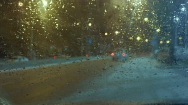 Arabanın ön camından yol manzarası. Üzerinde yağmur veya kar damlaları var.