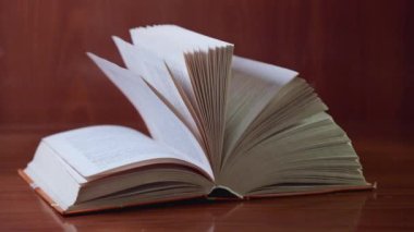 Bir sürü sallanan sayfası olan açık bir kitap masanın üzerinde yatıyor..