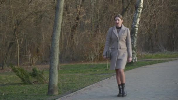 Kobieta Średnim Wieku Jasnym Płaszczu Idzie Chodnikiem Kierunku Kamery — Wideo stockowe
