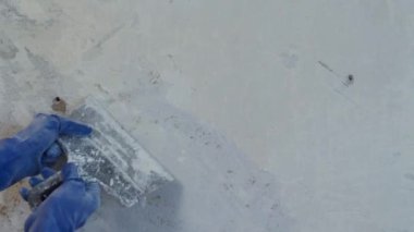 Eski bir duvardan metal bir spatulayla eski bir boyayı çıkarıyorum. Evde resim yapmaya hazırlanıyorum.