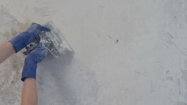 Mavi eldivenli kadının elleri eski boyayı spatulayla kazıdı..