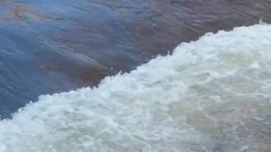 Beyaz köpüklerin oluşturduğu eşik üzerinde güçlü bir dağ nehri akıntısı..