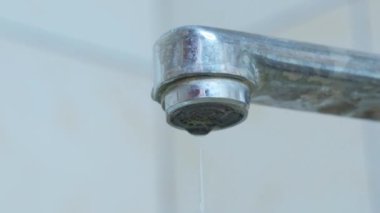 Su eski musluktan damlıyor, yakın plan...