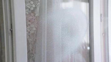 Kadının eli cam camını köpük deterjanıyla yıkıyor...