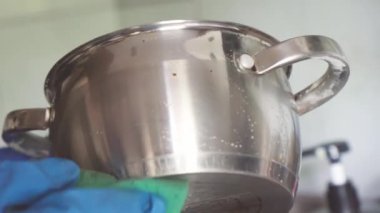 Mavi eldiven, metal tavayı süngerle yıkar...