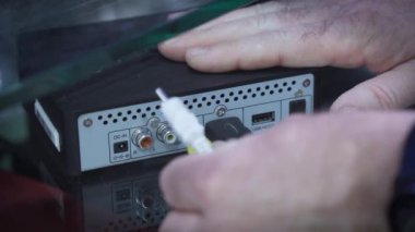 İnsan eli TV seti kutusuna ses kablosu bağlar.