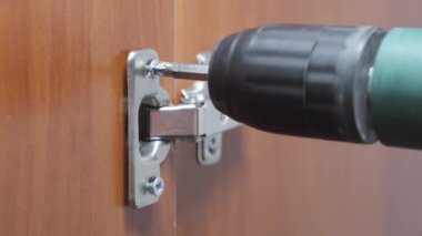 Tahta bir dolaba kapı menteşesi yerleştirirken vidayı sıkılaştır..