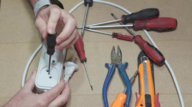 Elektrik prizi uzatma kablosunu tamir eden elektrikçinin elleri..