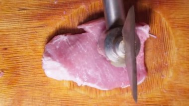 Et pirzolası pişiriyorum. Çekiçle et parçasına vur. Üst görünüm..