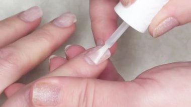 Kadının tırnağına renksiz cila sürüyorum. Yakın plan...