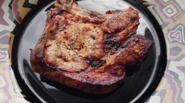 Siyah tabakta altın kabuklu lezzetli bir ızgara et..