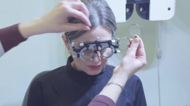 Göz muayenesine tabi tutulan bir kadın göz doktorunun ofisinde deneme aşamasında...