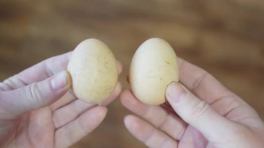 İki el, tahta arka planda iki taze yumurtayı tutuyor...