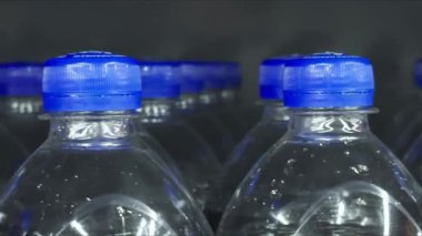 Depo raflarında karbonatlı tatlı içeceklerle dolu sıra sıra plastik şişeler..