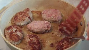 Çatal ve spatulayla et köftelerini tavaya fırlatan bir kadının yakın çekimi..