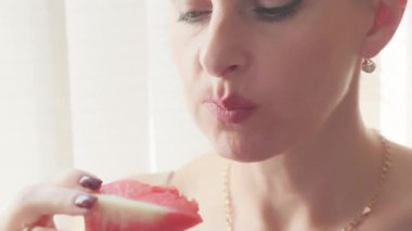 Sıcak bir yaz gününde sulu bir dilim karpuz yiyen bir kadının yakın plan portresi..