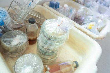 Bitmiş tarım plakaları ve test tüpleri sterilize edilmeyi ve tekrar kullanılmak üzere temizlenmeyi bekliyor. Laboratuvar ve bilim konsepti deneyi.