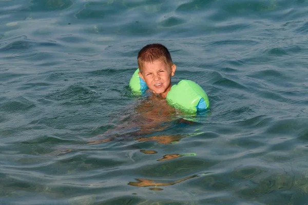 海で腕バンドと一緒に泳いでいる間に幸せな子供 — ストック写真