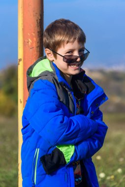 Metal çubuğa yaslanmış bir çocuk. Bir çocuk kale direğine yaslanıyor.