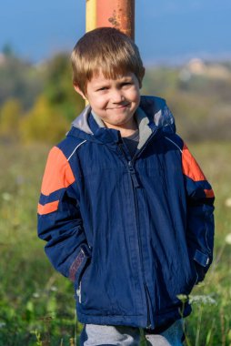 Metal çubuğa yaslanmış bir çocuk. Bir çocuk kale direğine yaslanıyor.