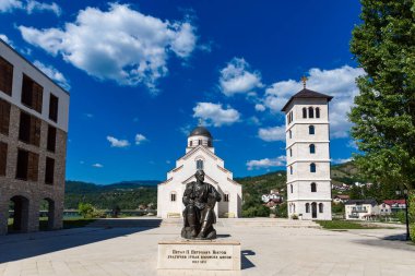 Visegrad, Bosna-Hersek Cumhuriyeti - 13 Ağustos 2023: Andricgrad 'daki St. Lazar Kilisesi ve Petar II Petroviç Njegos anıtı. Film yönetmeni Emir Kusturica 'nın inşaat projesi.