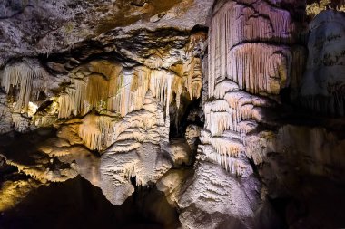 Exploring beautiful Postojna cave in Slovenia the most visited european cave. Thousands of stalagmites and stalactites clipart