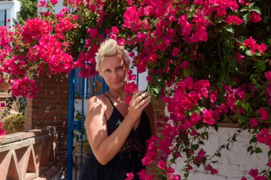 A beautiful woman with short hair poses in the city of Frigiliana, Spain. Beautiful woman in cyclamen flowers clipart