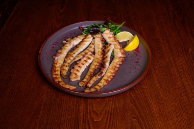 Tabağında limon olan ızgara ahtapot. 