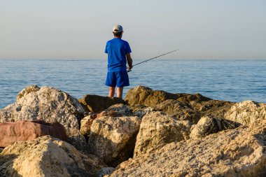 Malaga, İspanya - 06 Ağustos 2024: Bir adam kayalıklarda balık tutuyor.