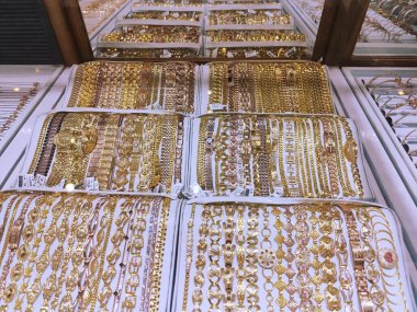 Altın mücevherlerin, kolyelerin, yüzüklerin, bileziklerin cam bir kutuda fotoğrafı.