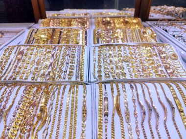 Altın mücevherlerin, kolyelerin, yüzüklerin, bileziklerin cam bir kutuda fotoğrafı.