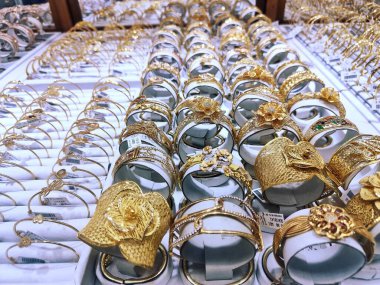 Altın mücevherlerin, kolyelerin, yüzüklerin, bileziklerin cam bir kutuda fotoğrafı.