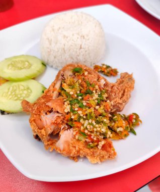 fast food fried chicken with raw chili sauce, cucumber slices and rice balls, also called ayam penyet in Indonesia clipart