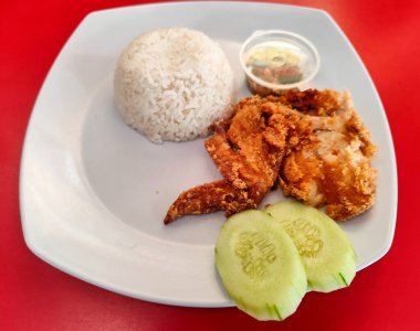 Çiğ biber soslu kızarmış tavuk, salatalık dilimleri ve pirinç topları, Endonezya 'da ayam penisi olarak da bilinir.