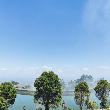 beautiful view of embung or artificial lake at the top of the hills with a bright blue sky clipart