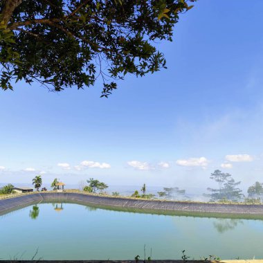 beautiful view of embung or artificial lake at the top of the hills with a bright blue sky clipart