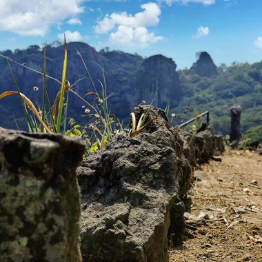 Tepedeki büyük kayanın arkasında güzel bir manzara var.