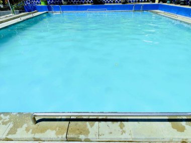 Temiz mavi suyu olan yüzme havuzu, paslanmaz çelikten tırabzanlar.