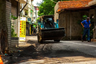 Yol tamircileri yolda asfalt döşüyorlar.
