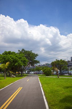 Nehir parkının temiz bisiklet yolu Mavi gökyüzü ve beyaz bulutların altında