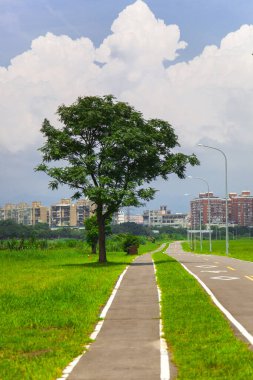 Nehir parkının temiz bisiklet yolu Mavi gökyüzü ve beyaz bulutların altında
